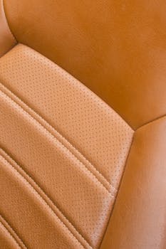 Detailed close-up of a classic car's vintage leather seat with rich texture and stitching.